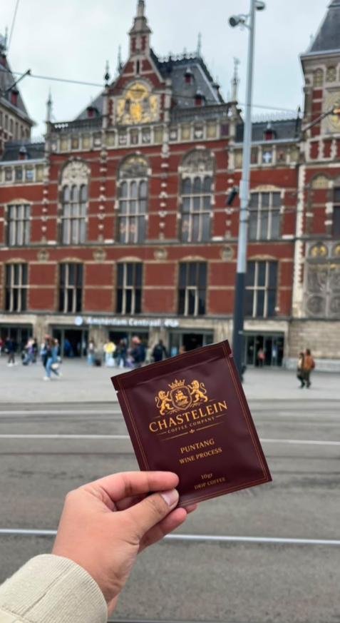 A Chastelein Puntang sachet held up in front of Amsterdam Centraal station